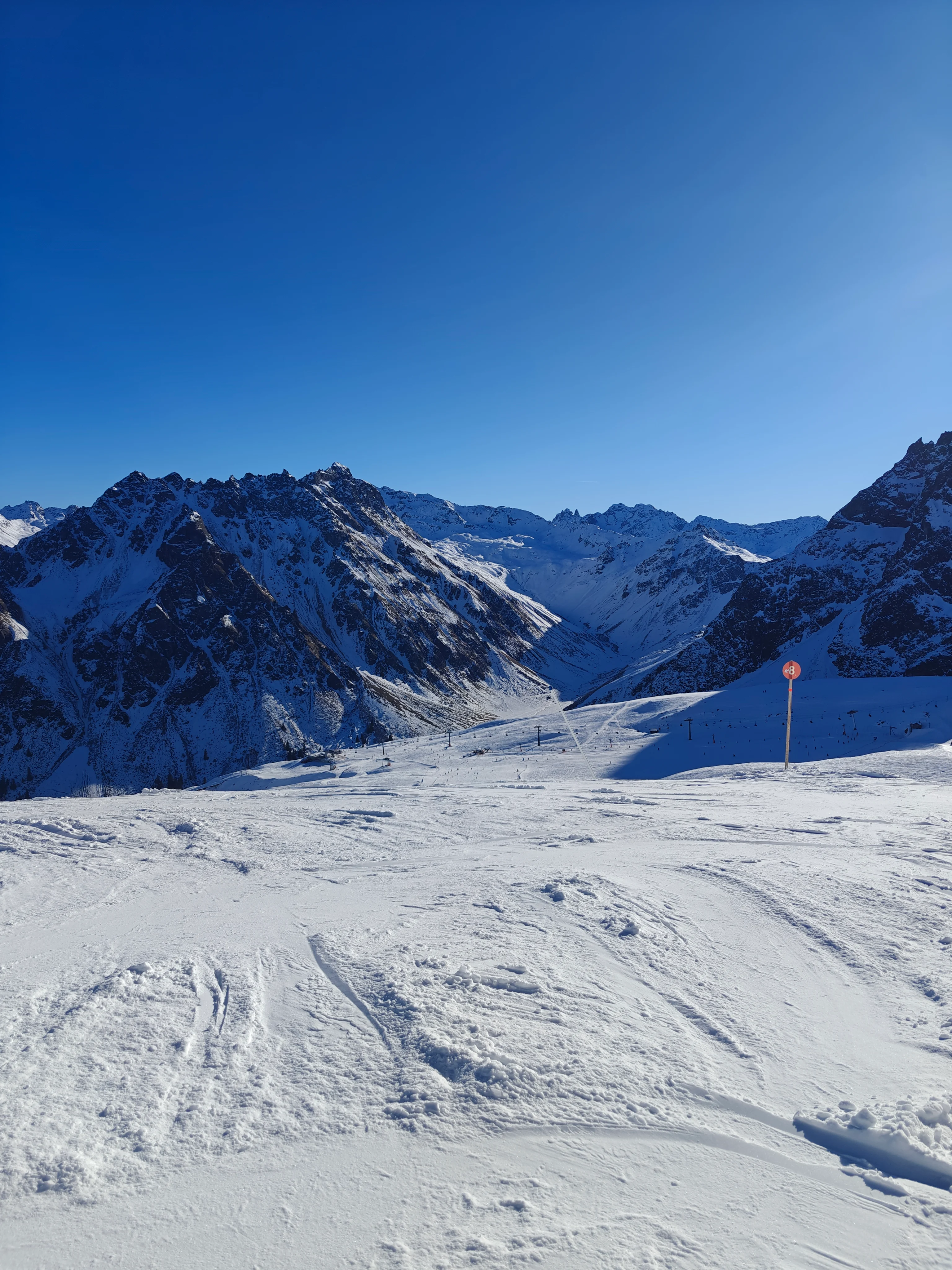 Verschneite Berglandschaft mit Skipiste unter blauem Himmel